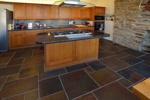 Kitchen features a central island, gas stove, oven, microwave, and tiled backsplash.