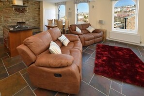 Relax in this cozy living space with a leather sofa, armchair, and fireplace.