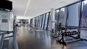 Un gimnasio moderno con diverso equipamiento de ejercicio, amplias ventanas y un diseño limpio y espacioso.