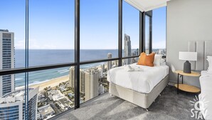 Habitación de hotel moderna con un amplio ventanal que ofrece vistas a la ciudad y a la playa.