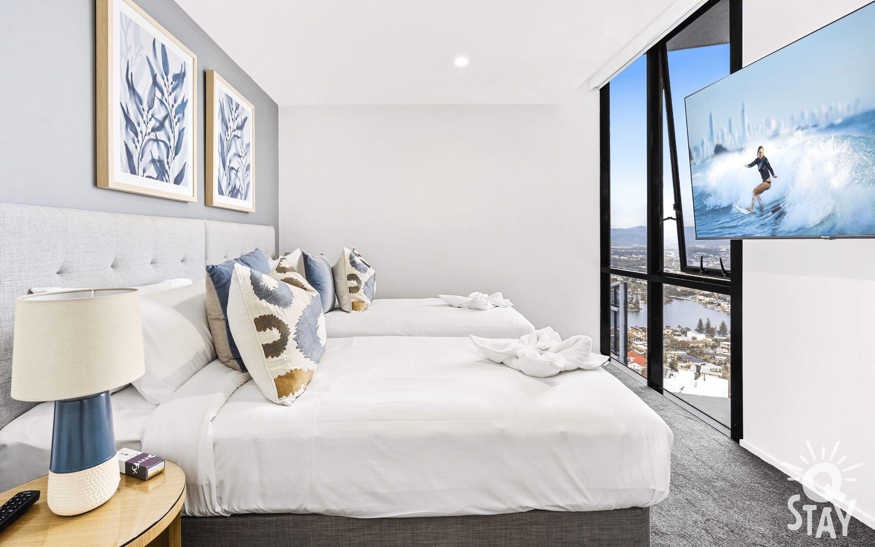 Habitación de hotel con dos camas, televisión y vista a la ciudad.