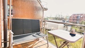 A balcony with a retractable sunshade, a small table, and a chair. - Wohnung Wesernest in Büsum (Büsum)