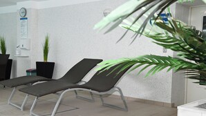 A waiting area with two lounge chairs, a clock, a wall-mounted information board, and potted plants. - Wohnung Wesernest in Büsum (Büsum)