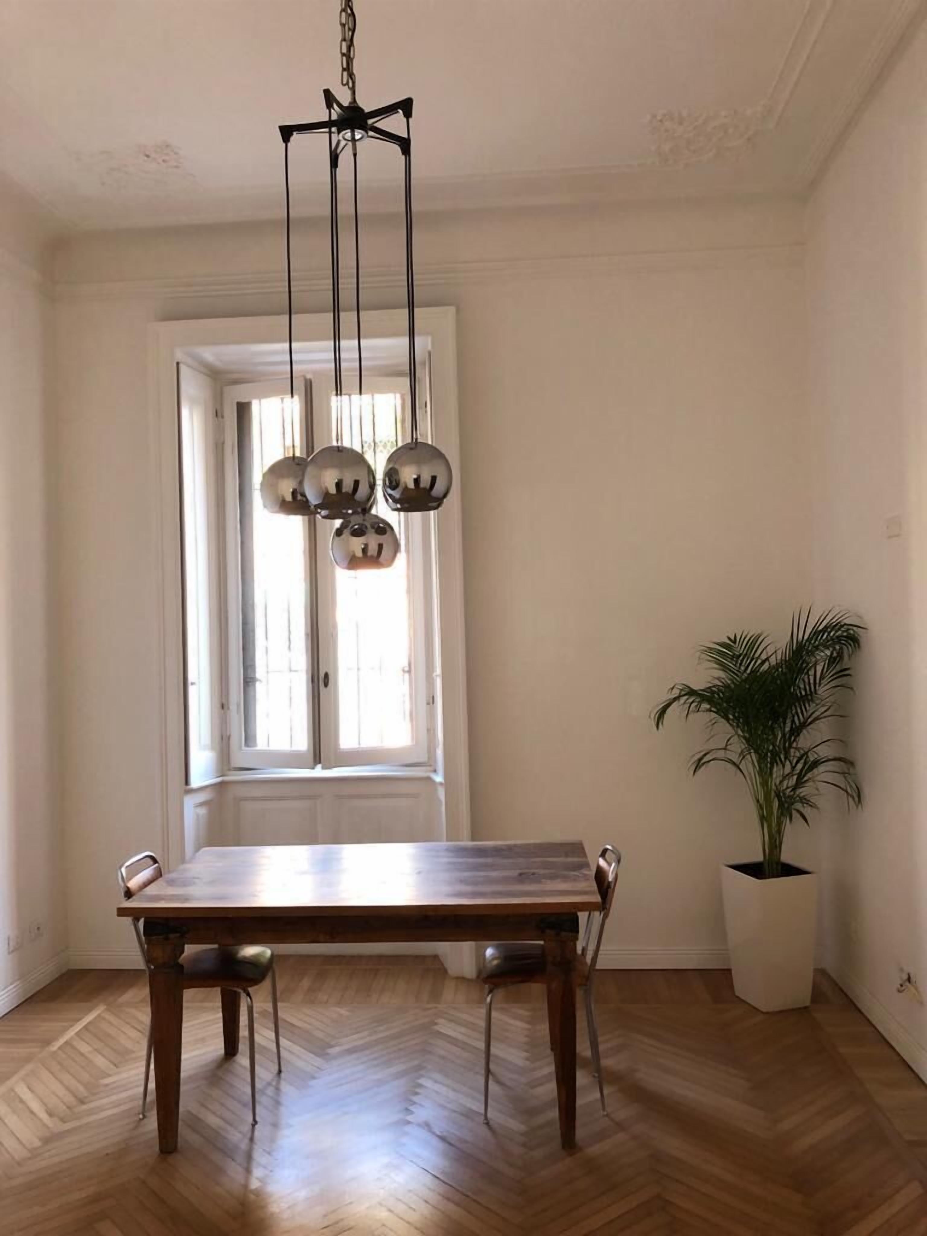A dining area with a wooden table, hanging pendant lights, and a potted plant.