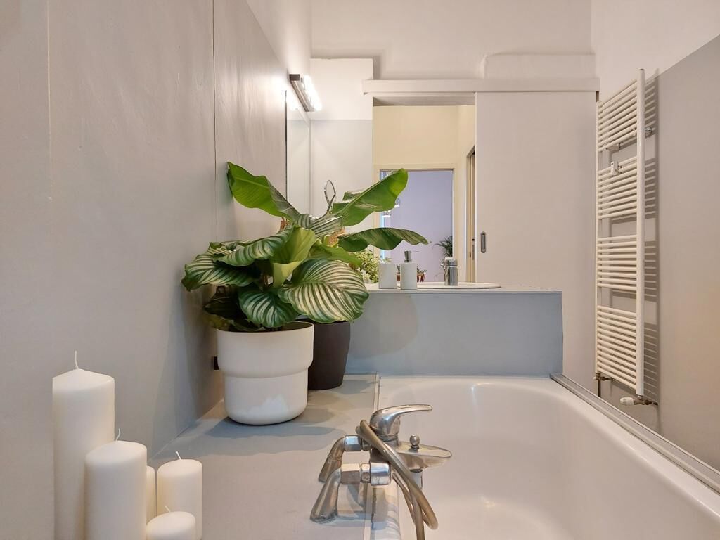 Une salle de bain moderne avec une baignoire, une plante en pot et un miroir.