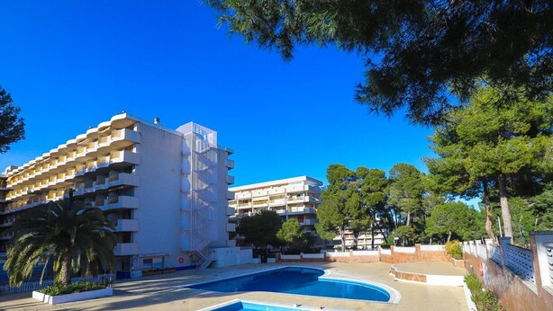 Un hôtel doté d’un espace piscine comprenant une grande piscine et une piscine plus petite, le tout entouré d’une clôture blanche et de verdure.