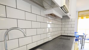 Une cuisine moderne avec des carreaux de céramique blancs disposés en motif métro, un évier en acier inoxydable et un plan de travail noir.