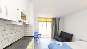 Une chambre d’hôtel compacte comprenant un coin cuisine, un canapé, deux lits et un espace repas.