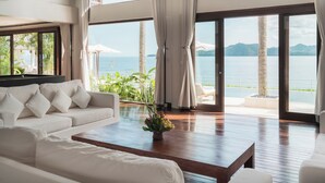 A spacious living room with a large window overlooking a beach and ocean. - Villa Blanca by Alfred in Bali (Manggis)