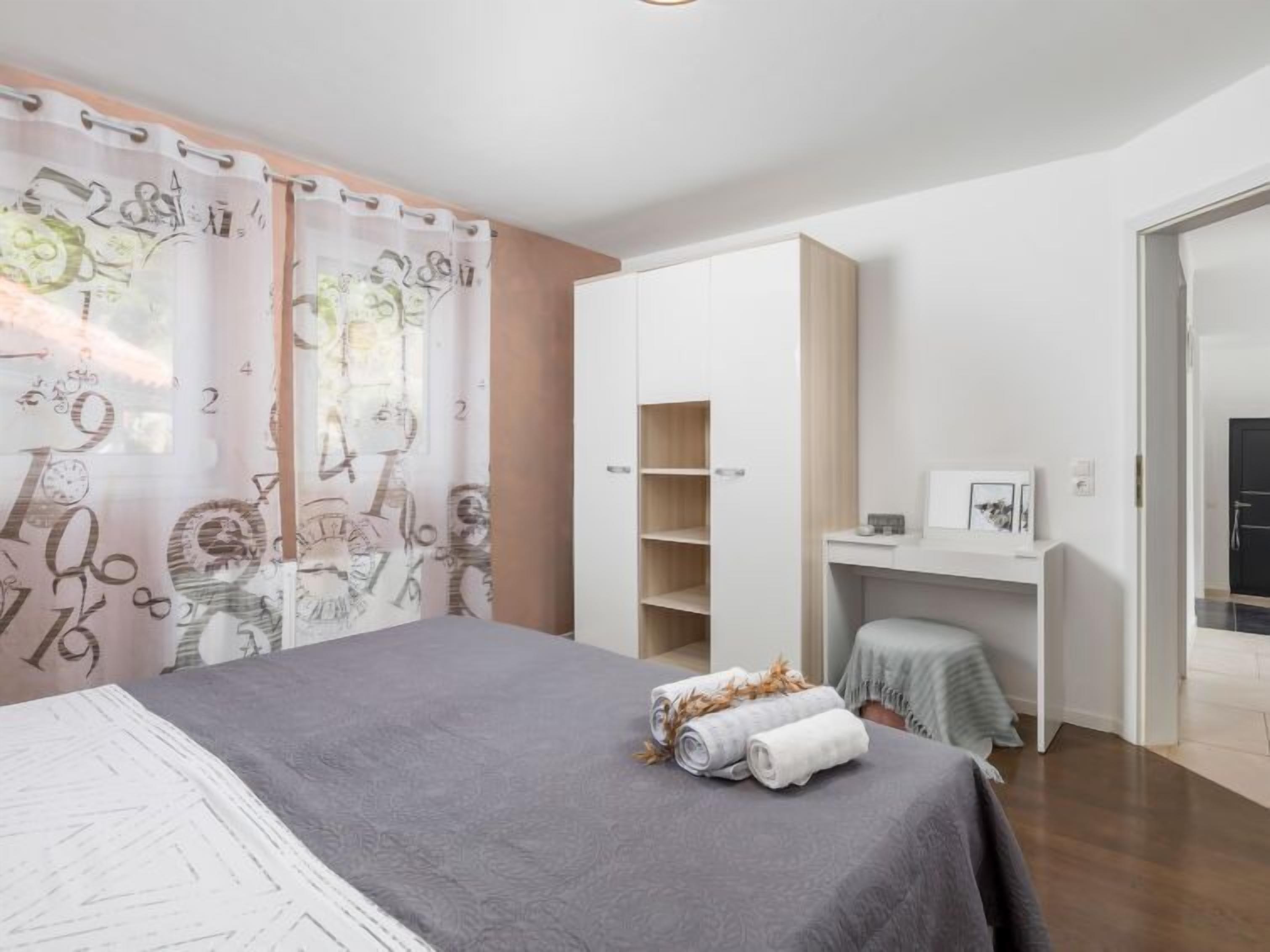 A modern bedroom with a bed, a desk, and a wardrobe.