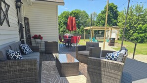 A deck with wicker furniture and a welcome sign. - Cozy Farmhouse w/ short walk to a private  lake
 (Delton)