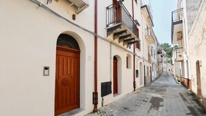 Une ruelle étroite pavée, bordée d’immeubles aux portes cintrées et aux balcons.