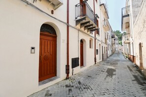 A narrow cobblestone street flanked by buildings with arched doorways and balconies. - Case Ruggieri Luxury apt: Don Pietro apartment (Gratteri)