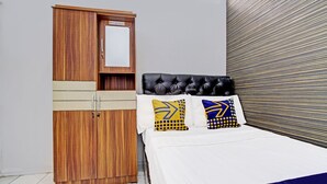 Ein Schlafzimmer mit einem Holzschrank, einem Bett mit schwarzem Kopfteil und einer gestreiften Wand.