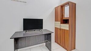 Ein Zimmer mit einem Flachbildfernseher auf einem dunklen Holztisch, einem Holzschrank mit Spiegel und einer kleinen Ablagefläche.