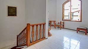 Ein geräumiger Raum mit einer Holztreppe, einem großen Bogenfenster und einer Sitzecke mit einer Bank und Stühlen.