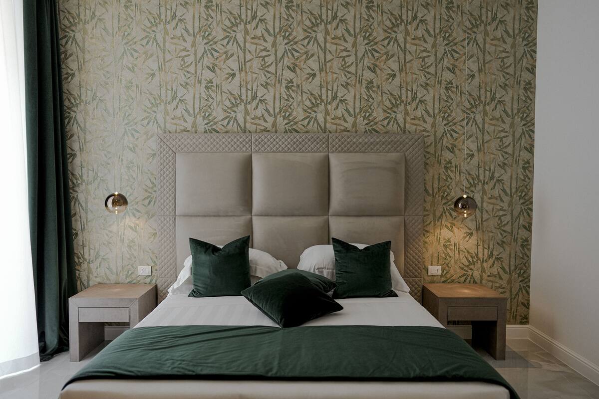 A neatly arranged bedroom with a large bed, two bedside tables, and a headboard with a quilted pattern.