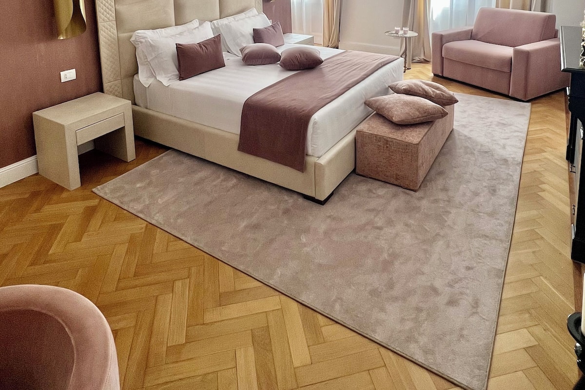 A modern bedroom with a large bed, a bedside table, a chair, and a small table.