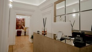A reception area with a wooden reception desk, a large mirror, and a wall-mounted telephone. - Màs Boutique Hotel (Rome)