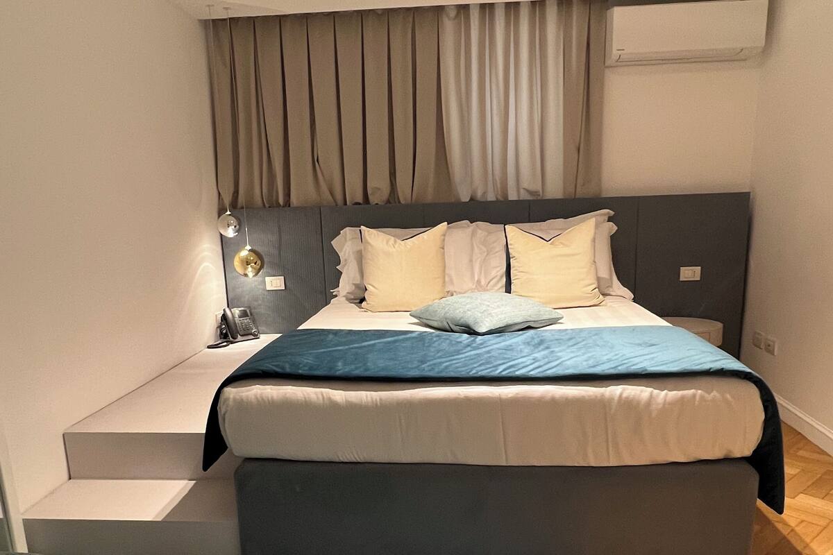 A modern bedroom with a bed, bedside tables, and a built-in bench.