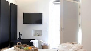 Un dormitorio moderno con cama, televisor, candelabro y un amplio ventanal.
