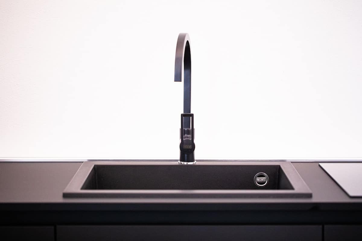 A modern kitchen sink with a sleek faucet and a black countertop.