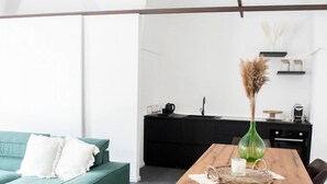 Un espacio habitable moderno con un sofá verde, una mesa de comedor de madera y una zona de cocina.