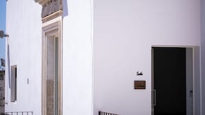 Un edificio blanco con un amplio arco de entrada y una puerta con un letrero encima.