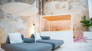 Un área de lounge moderna con un conjunto de sofás grises, una lámpara de techo blanca grande y un fondo de pared de ladrillo.