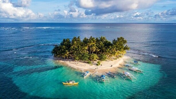 Eine Insel mit Strand, Palmen und klarem, blauem Wasser.