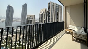 A balcony with a view of modern high-rise buildings and a river. - Manzil 4BR Penthouse in Dubai Creek w Harbour View (Dubai)
