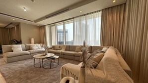 A spacious living room with a large sectional sofa, a round coffee table, and a decorative vase. - Manzil 4BR Penthouse in Dubai Creek w Harbour View (Dubai)