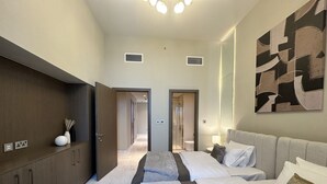 A hotel room with two beds, a wardrobe, a bathroom visible through an open door, and a modern abstract painting on the wall. - Manzil 4BR Penthouse in Dubai Creek w Harbour View (Dubai)