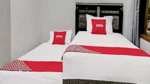 Una cama doble con dos almohadas rojas, ropa de cama blanca y un plaid estampado de leopardo.