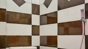 Un baño con inodoro, ducha y pared de azulejos con un diseño geométrico.
