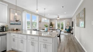 A spacious kitchen with a large island, white cabinetry, pendant lighting, and a view to the dining area. - Paradise Point Lakefront Getaway, Beach, Hot Tub (Mabank)