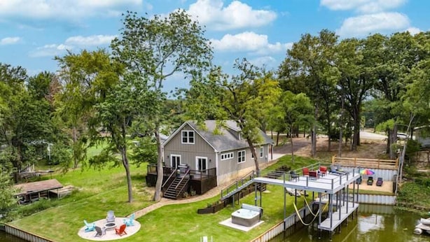 A house with a dock extending into a lake, surrounded by trees. - Paradise Point Lakefront Getaway, Beach, Hot Tub (Mabank)
