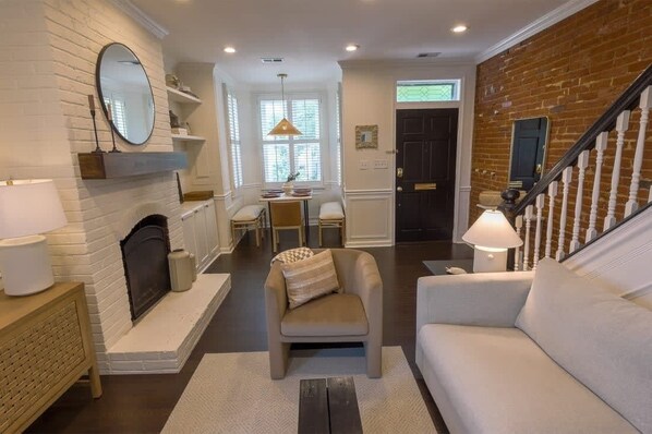 A living room with a fireplace, a dining area, and a staircase.
