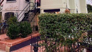 Un edificio de varios pisos con fachada de ladrillo, una escalera visible y un árbol con flores rosadas.