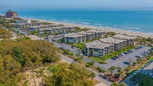 Un hôtel situé sur la côte, composé de plusieurs bâtiments à étages, doté d’un parking et offrant une vue sur la plage.