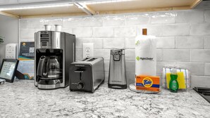 A kitchen with a coffee maker, toaster, kettle, and cleaning supplies. - Ocean Forest Villas Unit D215 - Ocean view (Myrtle Beach)