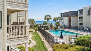 A pool area with lounge chairs, a fenced pool, and a view of the ocean. - Ocean Forest Villas Unit D215 - Ocean view (Myrtle Beach)