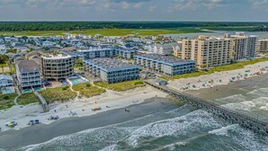 Un hôtel situé sur la côte, composé de plusieurs bâtiments, avec une plage et une jetée.