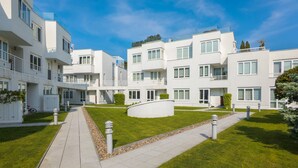 Un immeuble résidentiel moderne doté de nombreux balcons, d’une cour intérieure et d’une pelouse bien entretenue.