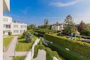 A modern residential area with neatly trimmed hedges, a clear pathway, and a white building with multiple windows.