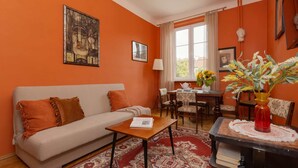 A living room with a sofa, coffee table, and a dining area with chairs and a table.