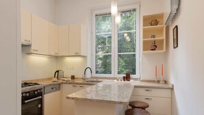 A modern kitchen with white cabinets, a granite countertop, a built-in oven, and a window with a view of trees.