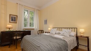 A bedroom with a large bed, two bedside tables with lamps, a desk, and chairs.