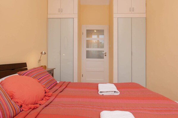 Une chambre à coucher avec un lit, des oreillers, une table de chevet et une armoire.