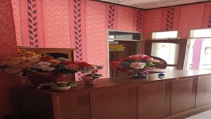 A reception desk with floral arrangements and a patterned wall. - Hotel O Aida Lestari (Sebulu)